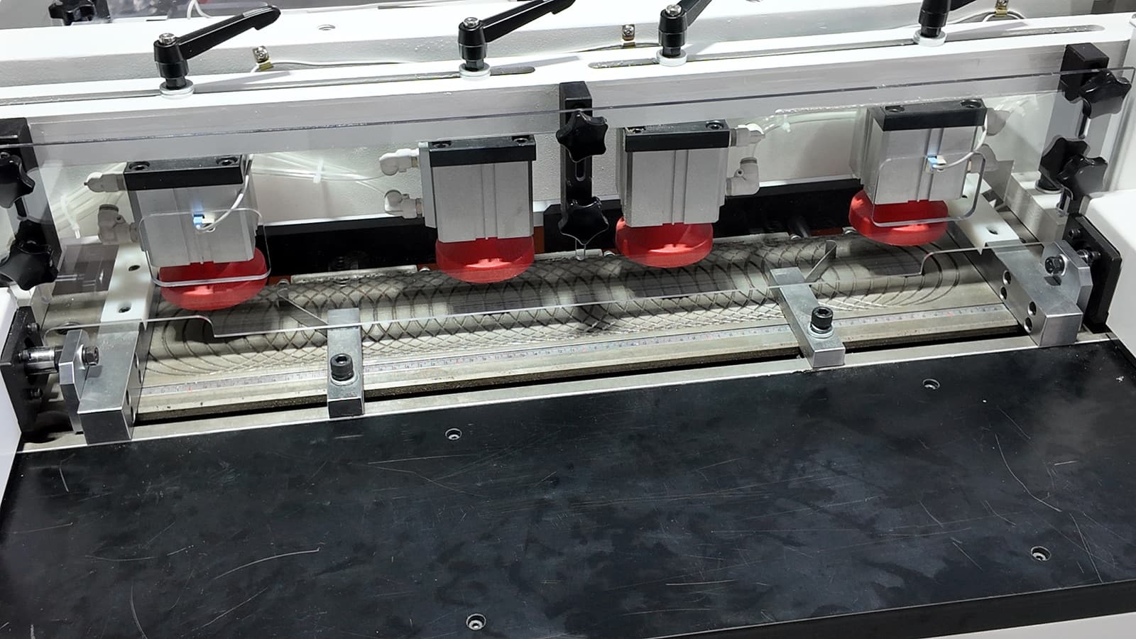 Close-up of the pneumatic hold-down clamps over the cutting area