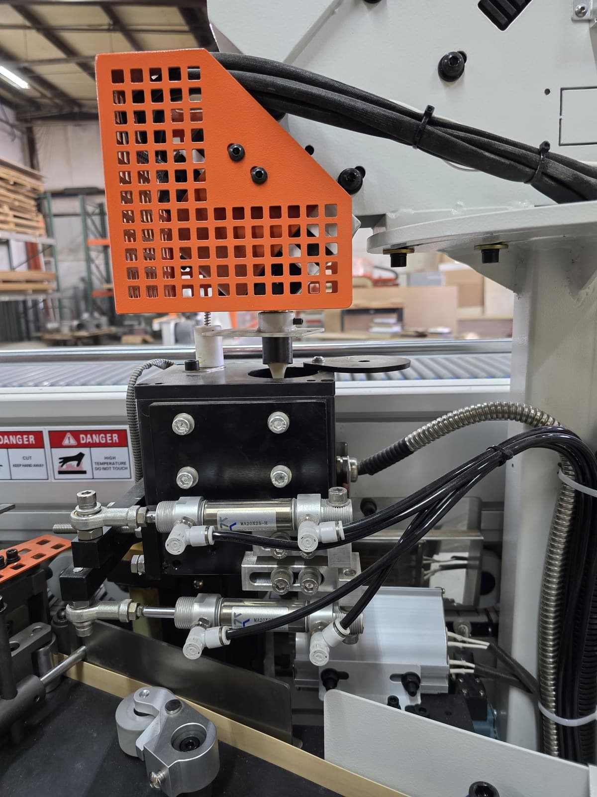 Glue station feed area with guard and pneumatic cylinders below the pellet hopper