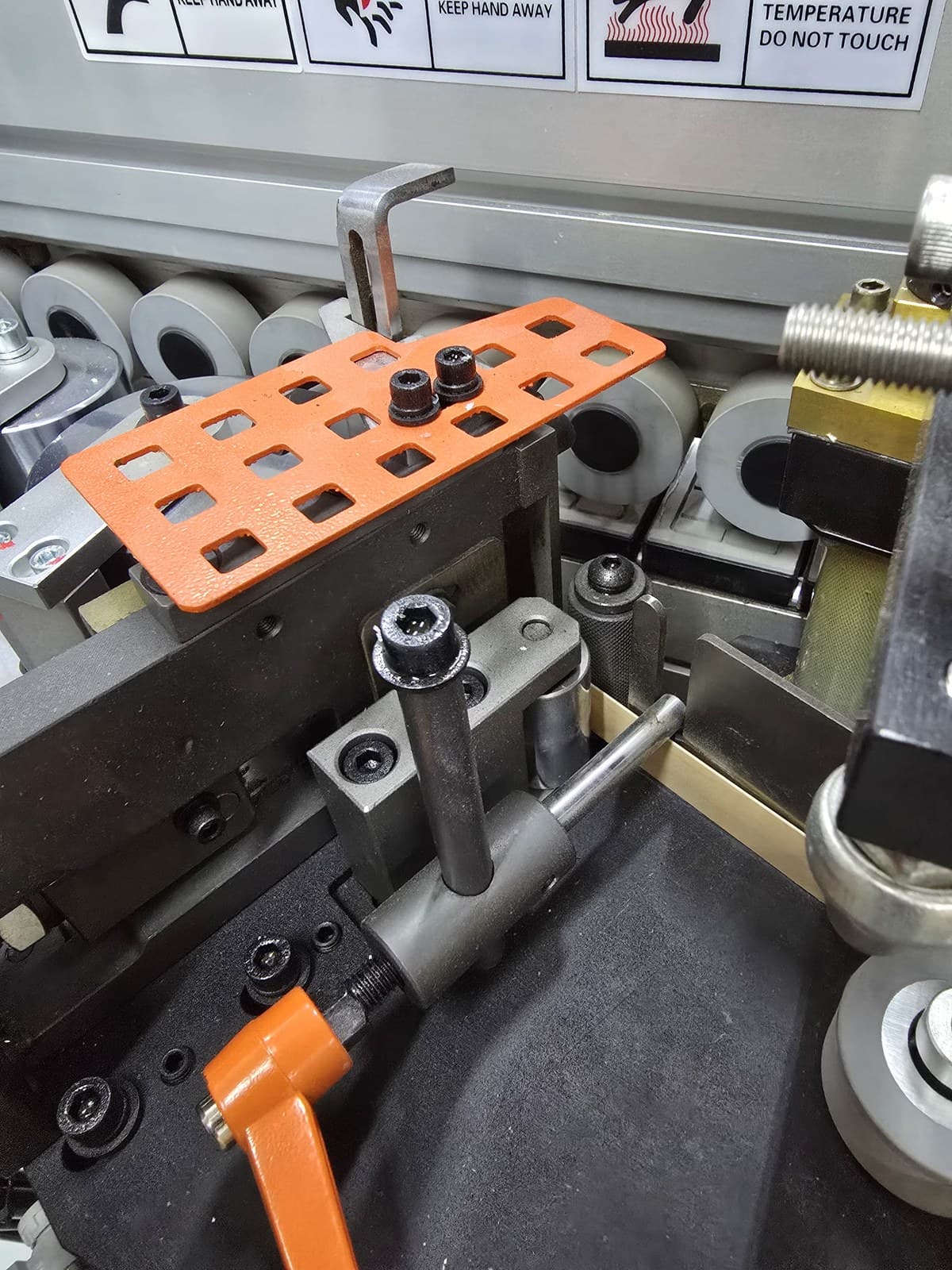 Hold-down wheels and adjustment hardware along the feed track