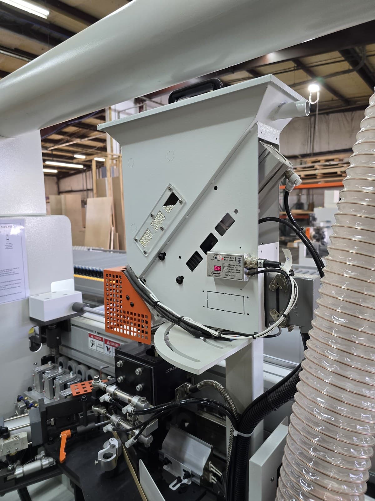 Glue pellet hopper viewed from the side with dust extraction hose