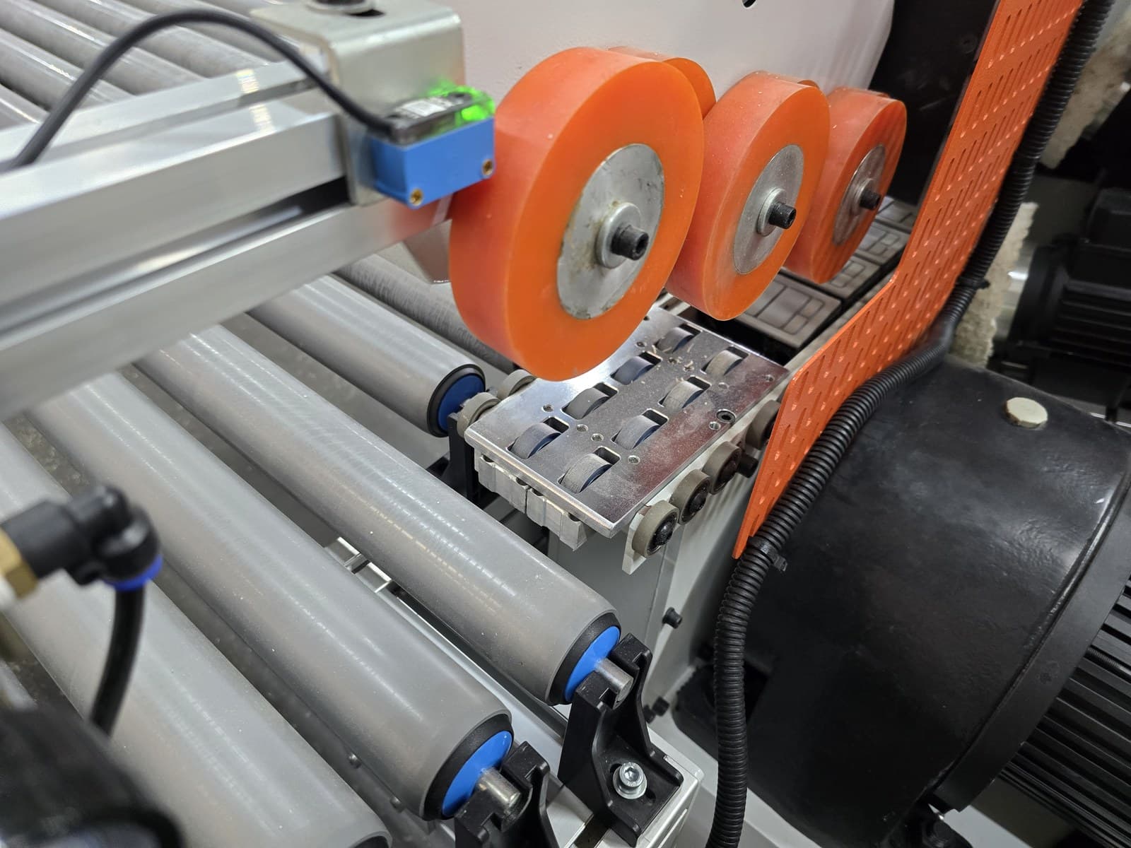 Motorized hold-down rollers over the transfer belts for small parts