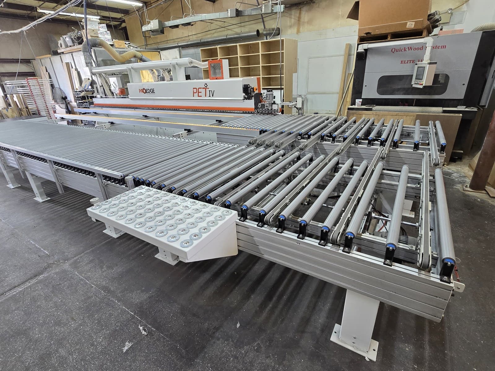 Wide view of the long part support table on the return conveyor with the PET IV behind