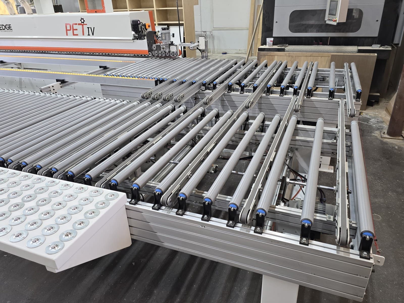 Outfeed and transfer station with timing tooth roller belts and return rollers