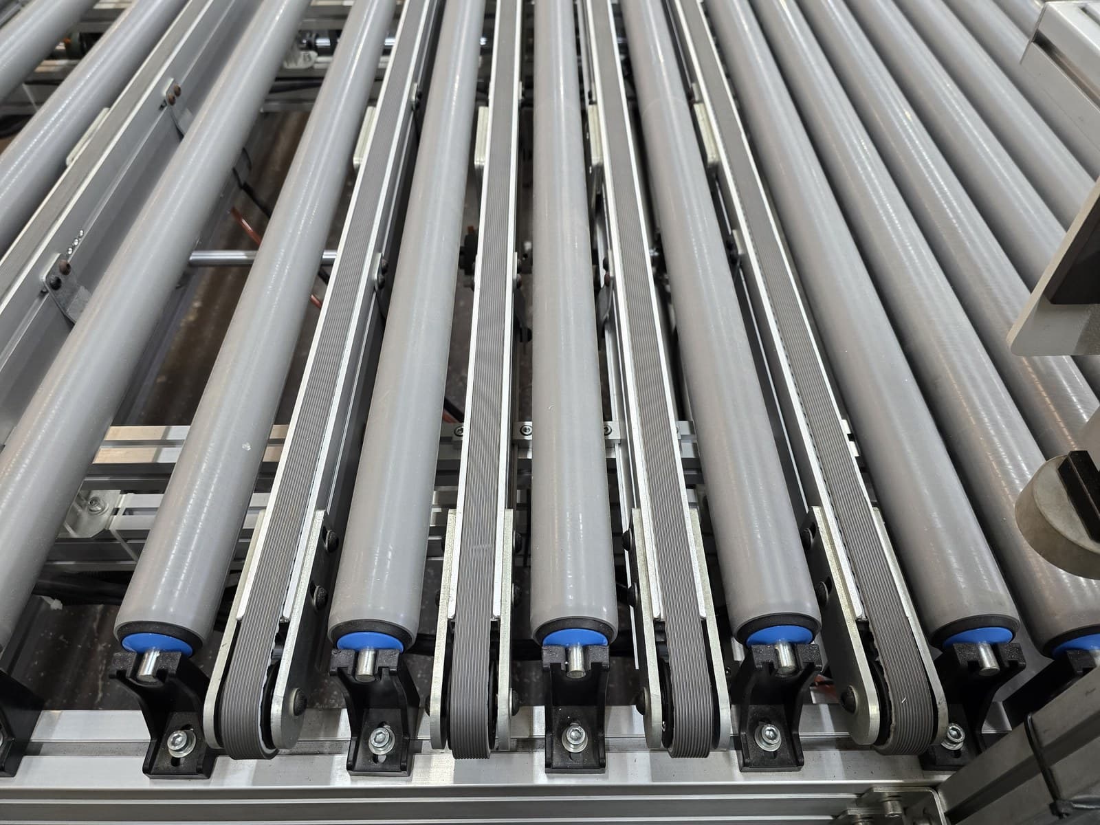 Return rollers with flat drive belts viewed along the conveyor