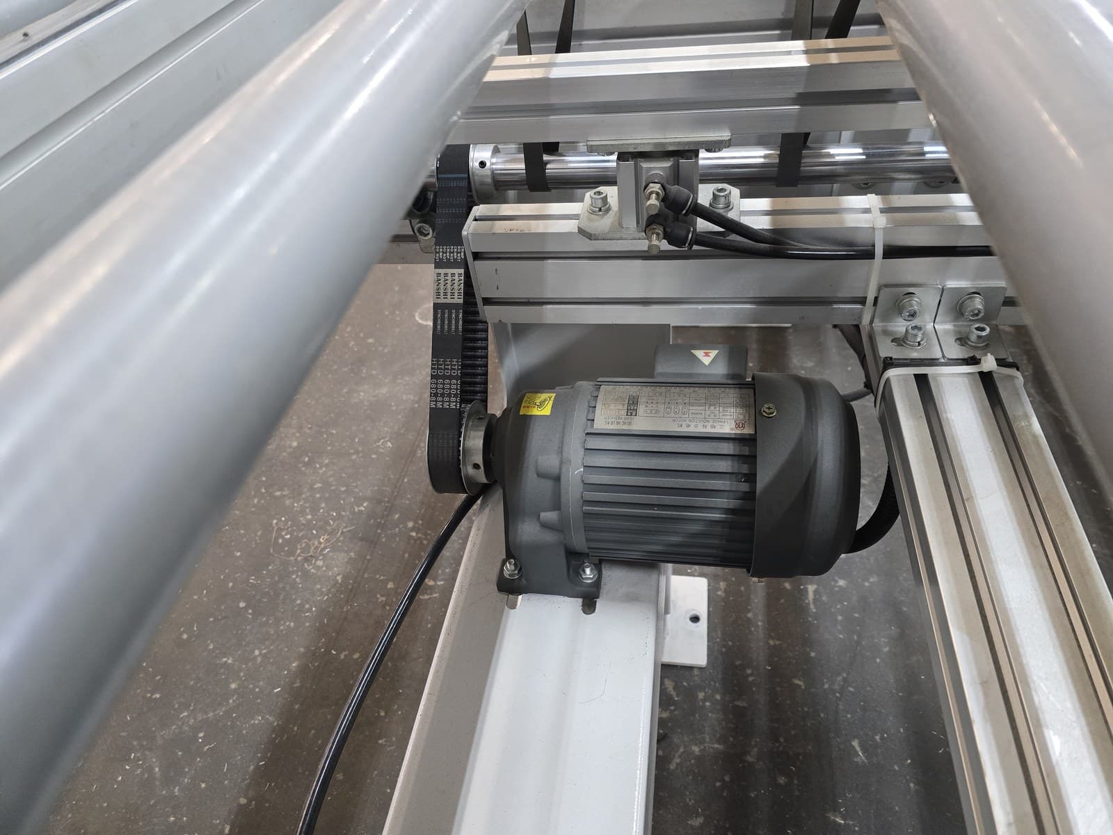 Roller drive motor and drive belt under the conveyor frame